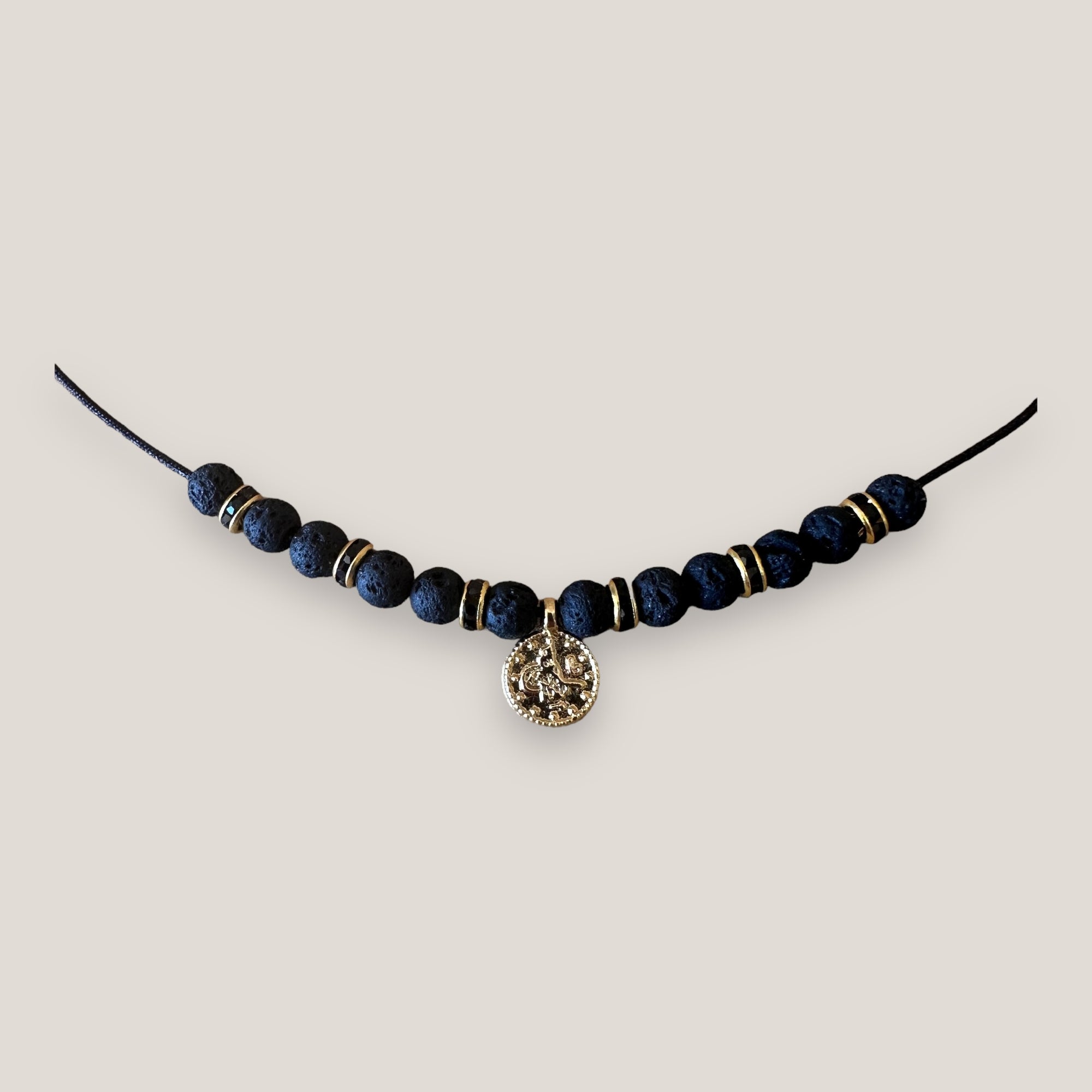 Collar midi con moneda tribal dorada, cuentas de lava negra y separadores oro y brillis negros