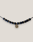 Collar midi con moneda tribal dorada, cuentas de lava negra y separadores oro y brillis negros