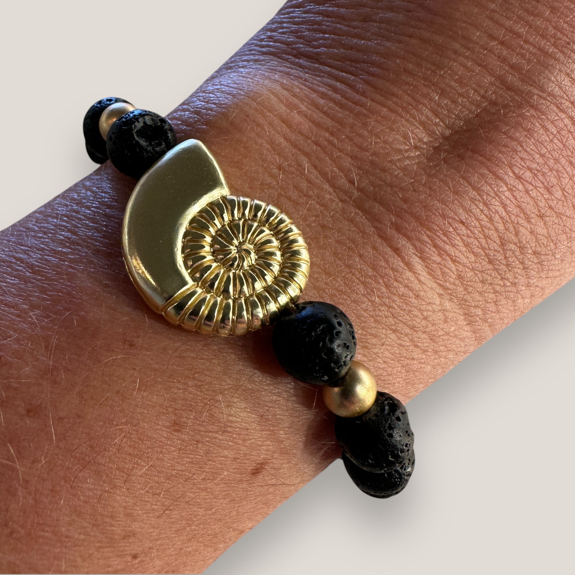 Pulsera con gran caracola y cuentas doradas con lava negra