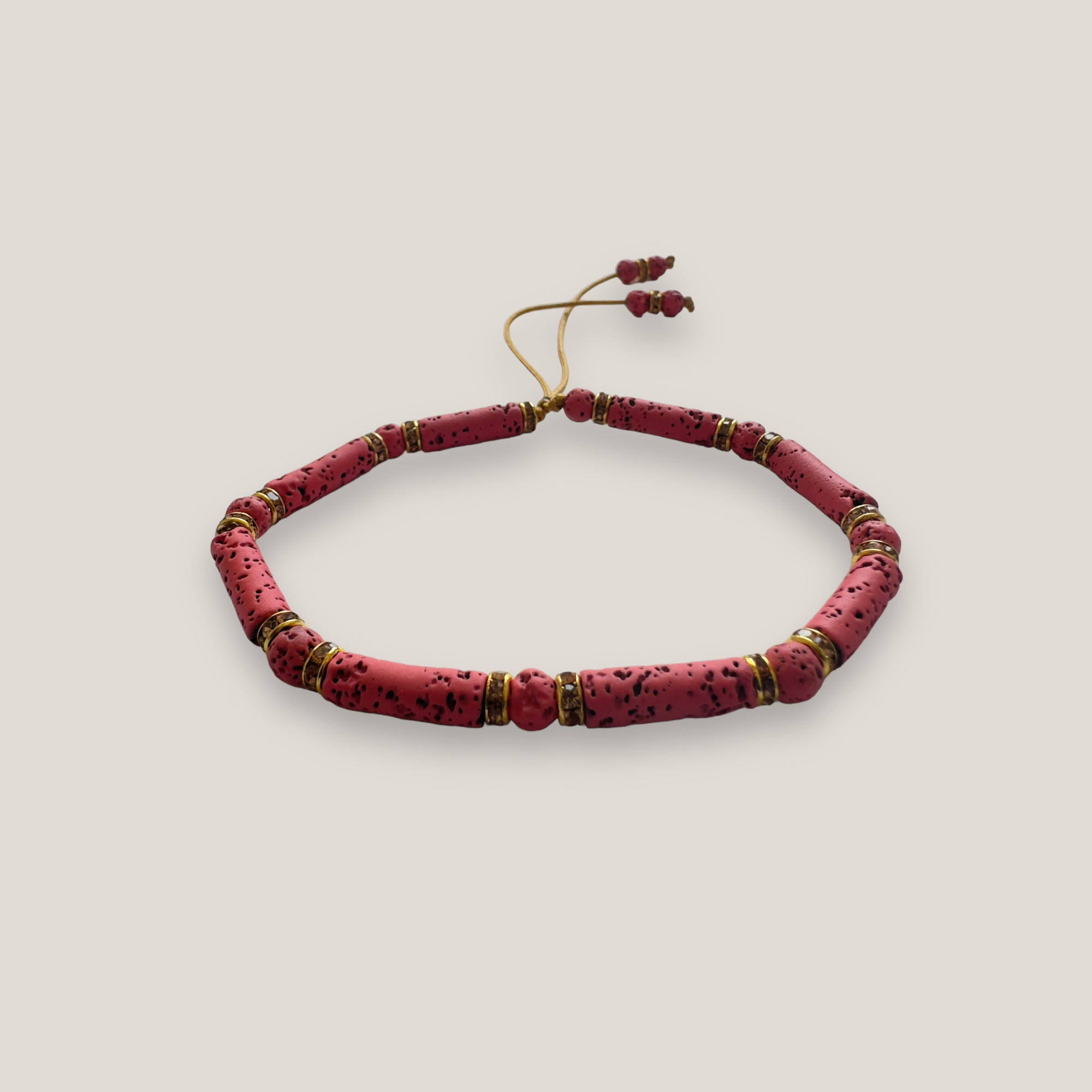 Pulsera con tubos y cuentas de lava fucsia y brillis oro con cristalitos rosas