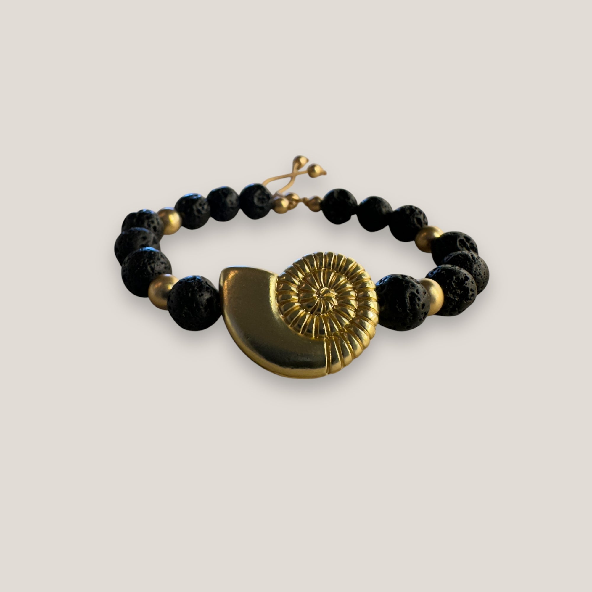 Pulsera con gran caracola y cuentas doradas con lava negra