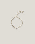 Pulsera minimal perla natural redondeada 6mm blanca cordón nailon dorado