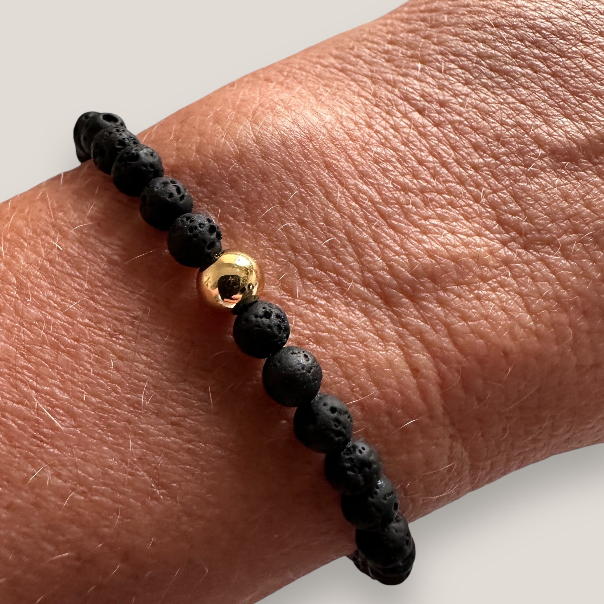 Armband mit goldener Stahlkugel und schwarzer Lava