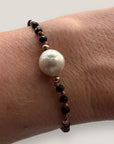 Pulsera Eloise negro con perla natural blanca, cristales facetados negros y sepatradores oro rosa