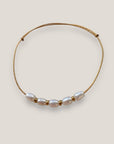 Pulsera minimal con hilera de cinco perlas naturales blancas, separadores de acero oro y cordón oro con nudos correderos