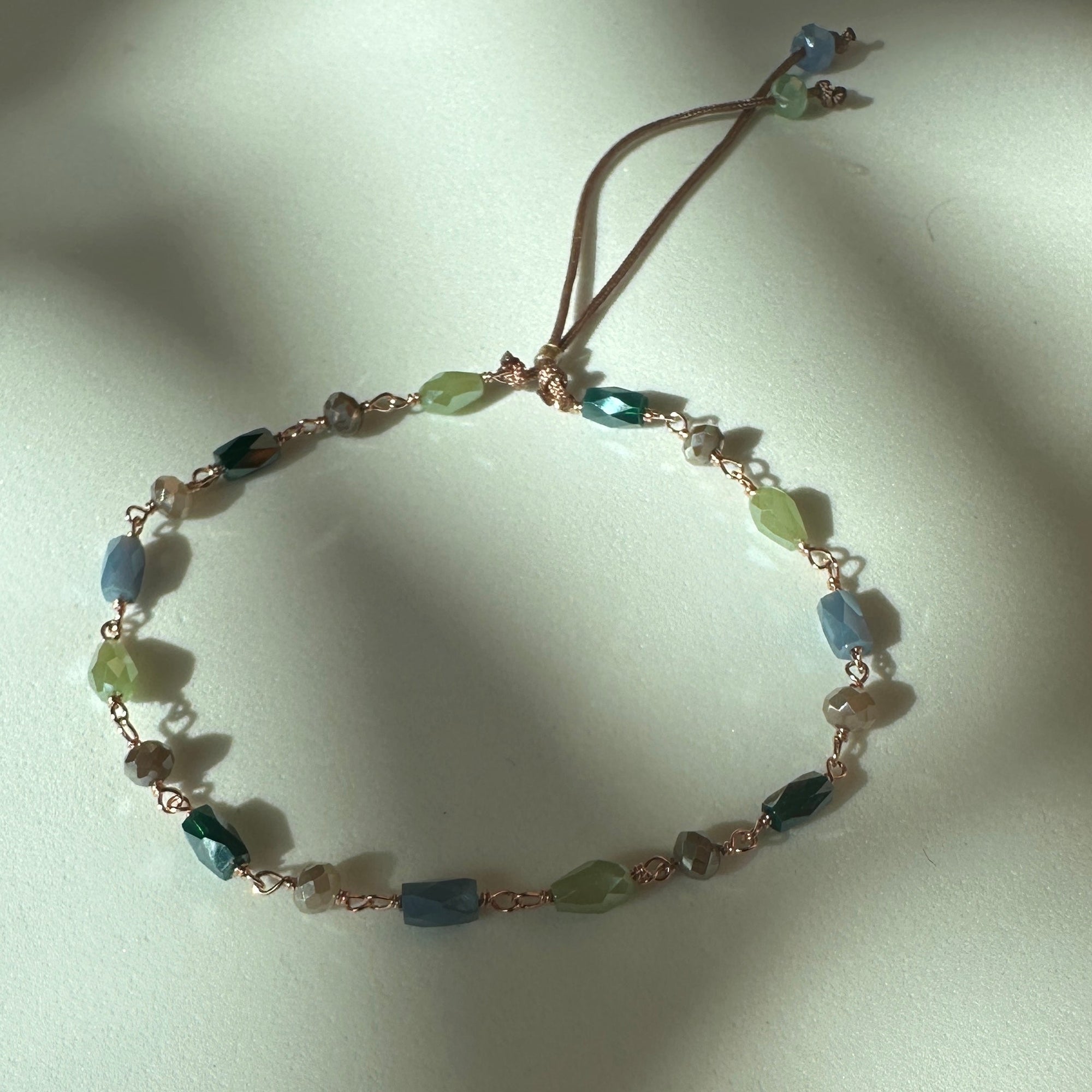 Pulsera Divino con cristales facetados verdes, azul y tostados pastel engarzados en oro rosa