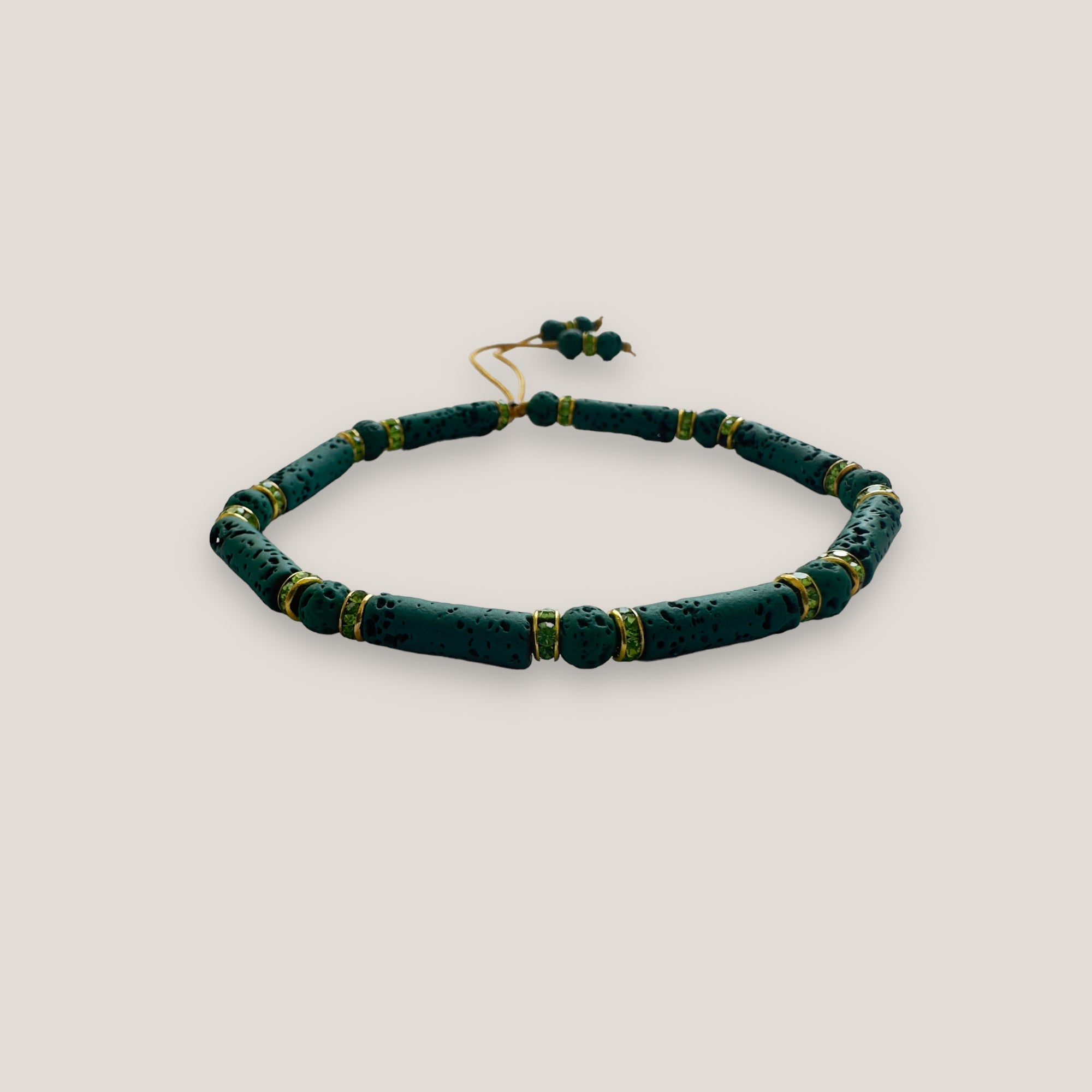 Pulsera con tubos y cuentas de lava verde oscuro y brillis oro con cristalitos color olivina