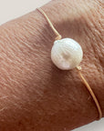 Pulsera minimal con gran perla natural blanca y cordón de nailon