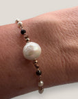 Pulsera Divino negro con perla natural blanca, cristales facetados negros y perlitas blancas naturales, engarces en oro rosa