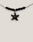 Collar midi con estrella dorada esmaltada en negro lava negra y separadores dorados con cristalitos negros
