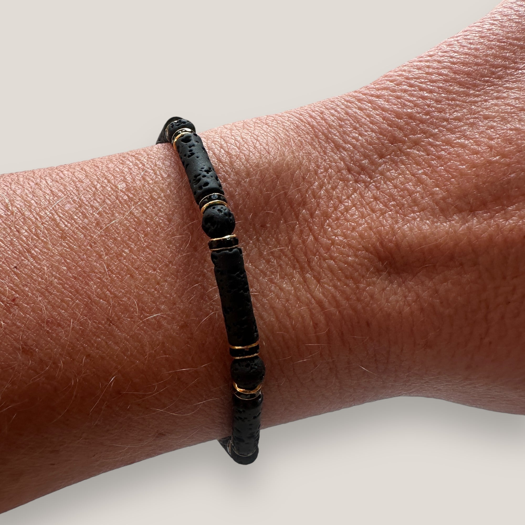 Pulsera con tubos y cuentas de lava negra y brillis oro con cristalitos negros