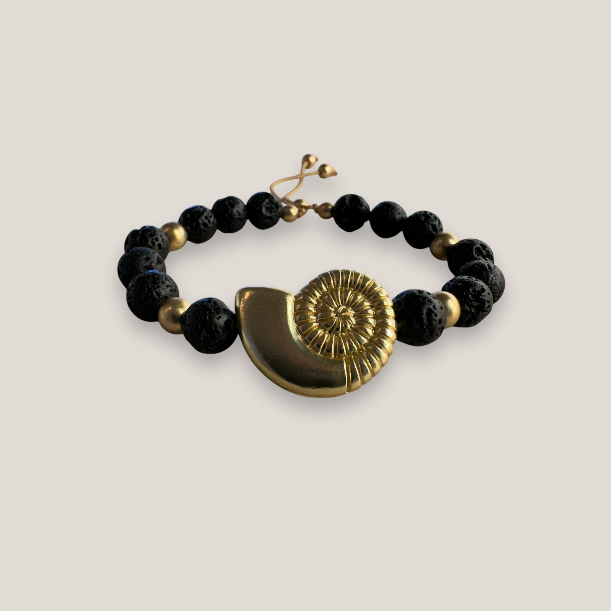 Pulsera con gran caracola y cuentas doradas con lava negra