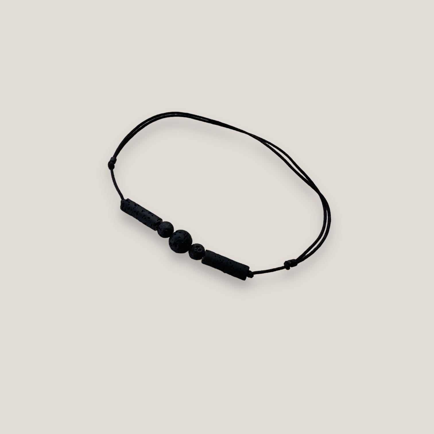 Pulsera minimal con una bola, dos bolitas y dos tubos de lava negra con nudos correderos
