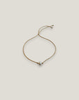 Pulsera minimal perla natural redondeada 6mm blanca cordón nailon dorado