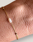 Pulsera minimal con perlita arroz y cordón oro con nudos correderos