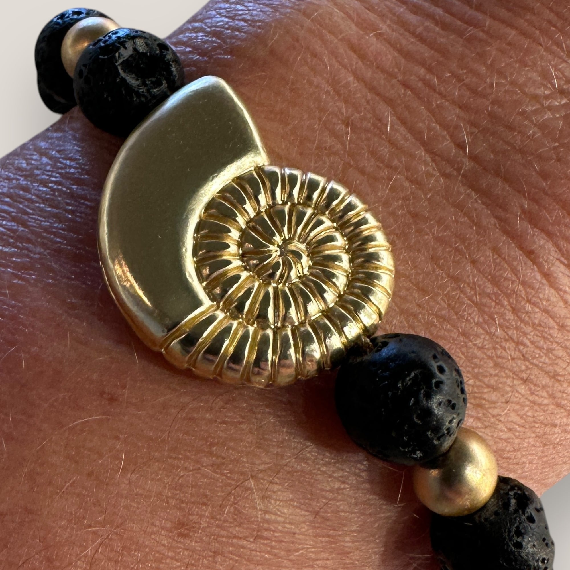 Pulsera con gran caracola y cuentas doradas con lava negra