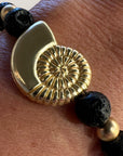 Pulsera con gran caracola y cuentas doradas con lava negra