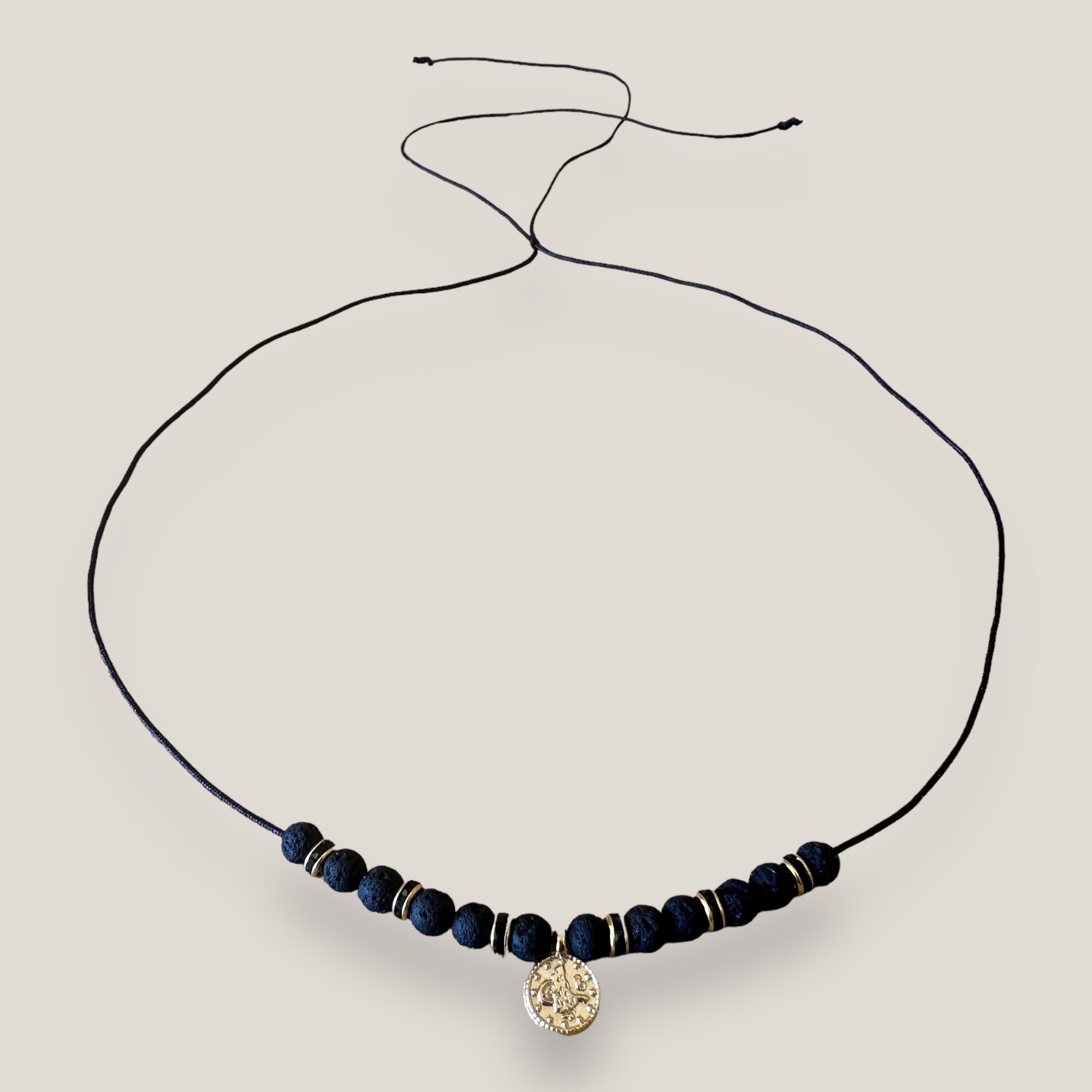 Collar midi con moneda tribal dorada, cuentas de lava negra y separadores oro y brillis negros