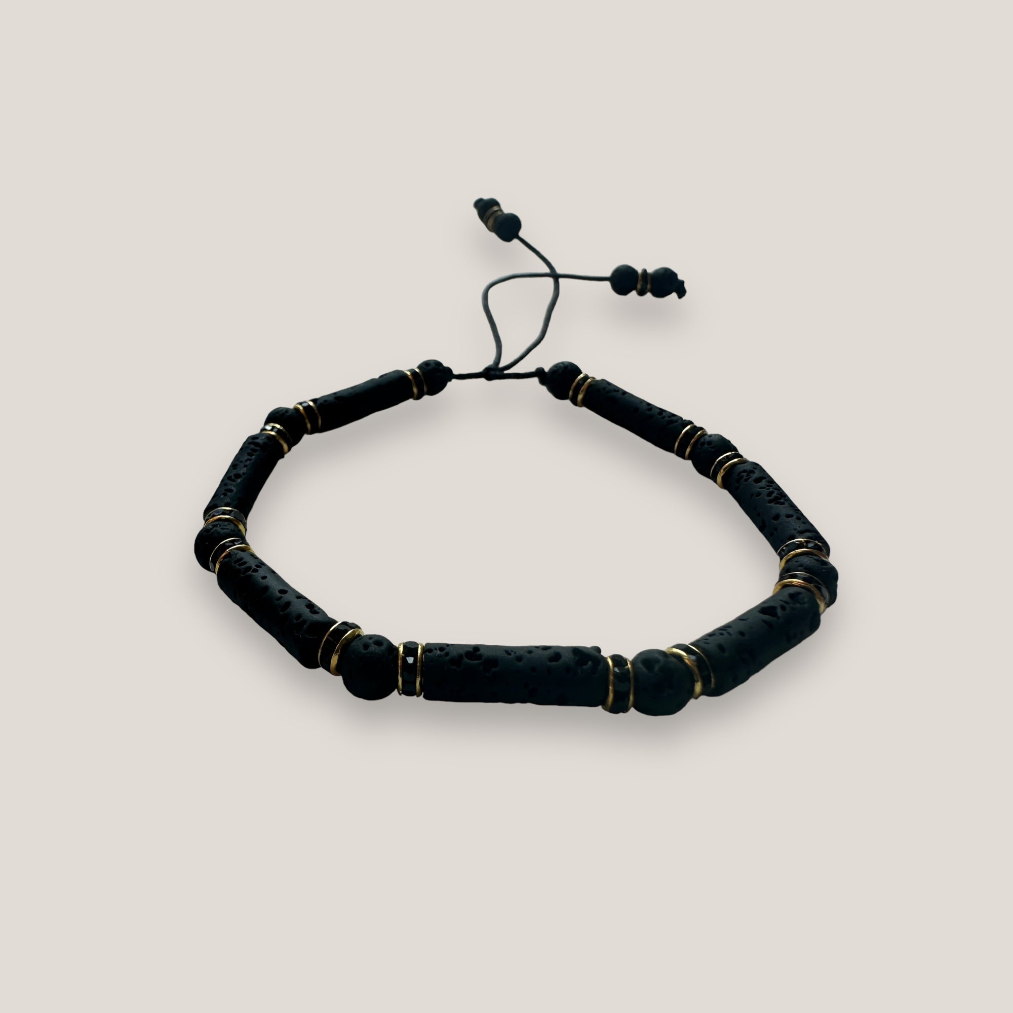 Pulsera con tubos y cuentas de lava negra y brillis oro con cristalitos negros