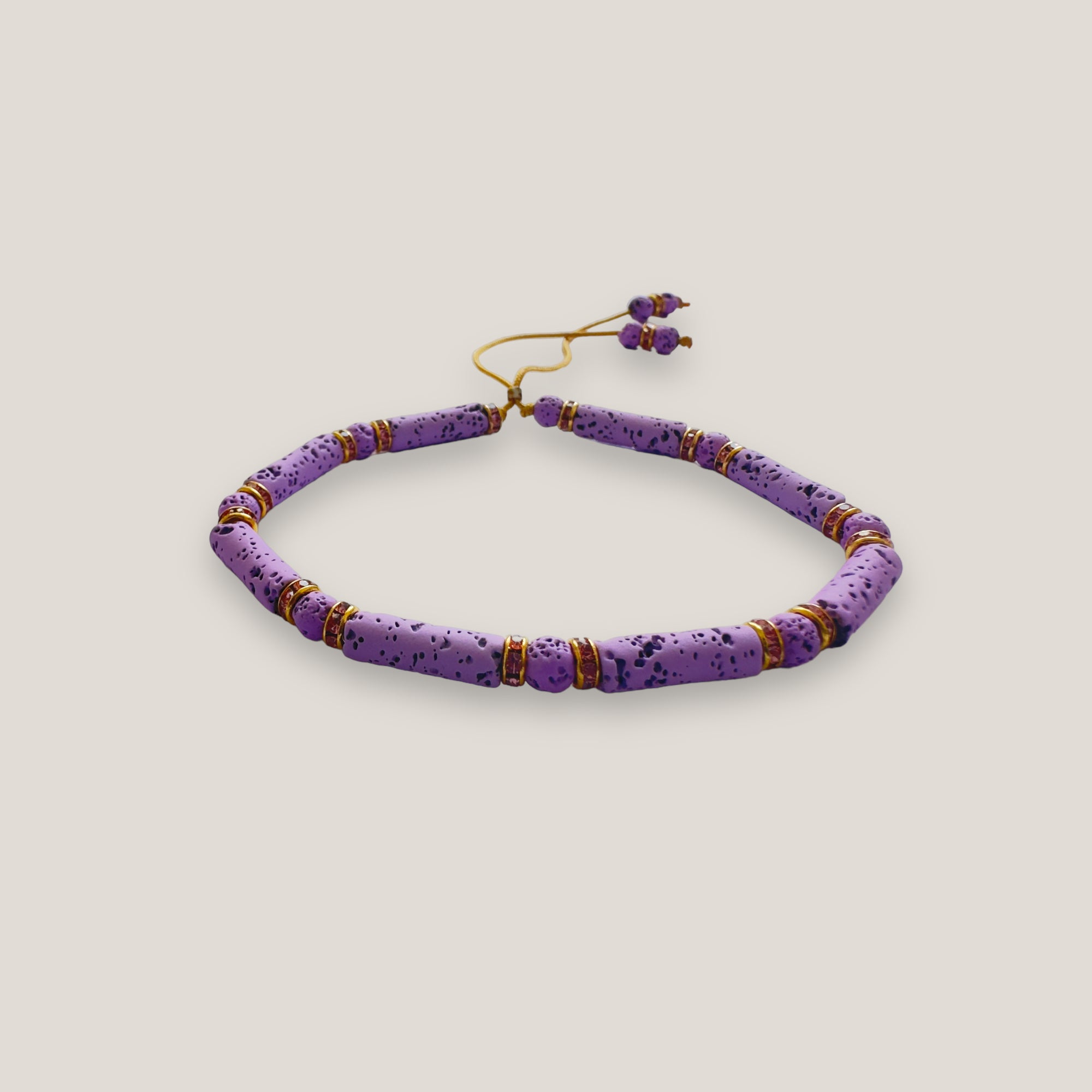 Pulsera con tubos y cuentas de lava malva y brillis oro con cristalitos rosas