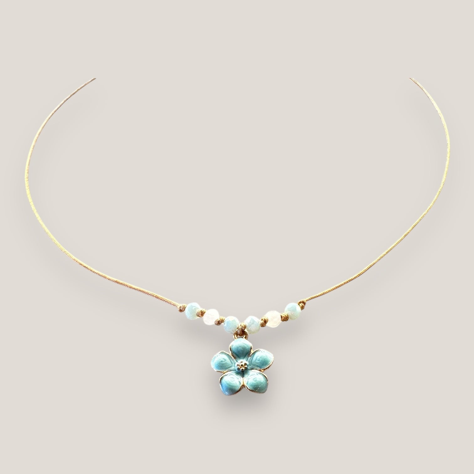 Collar midi con flor dorada esmaltada azul turquesa con cristales facetados en azul cielo y blanco