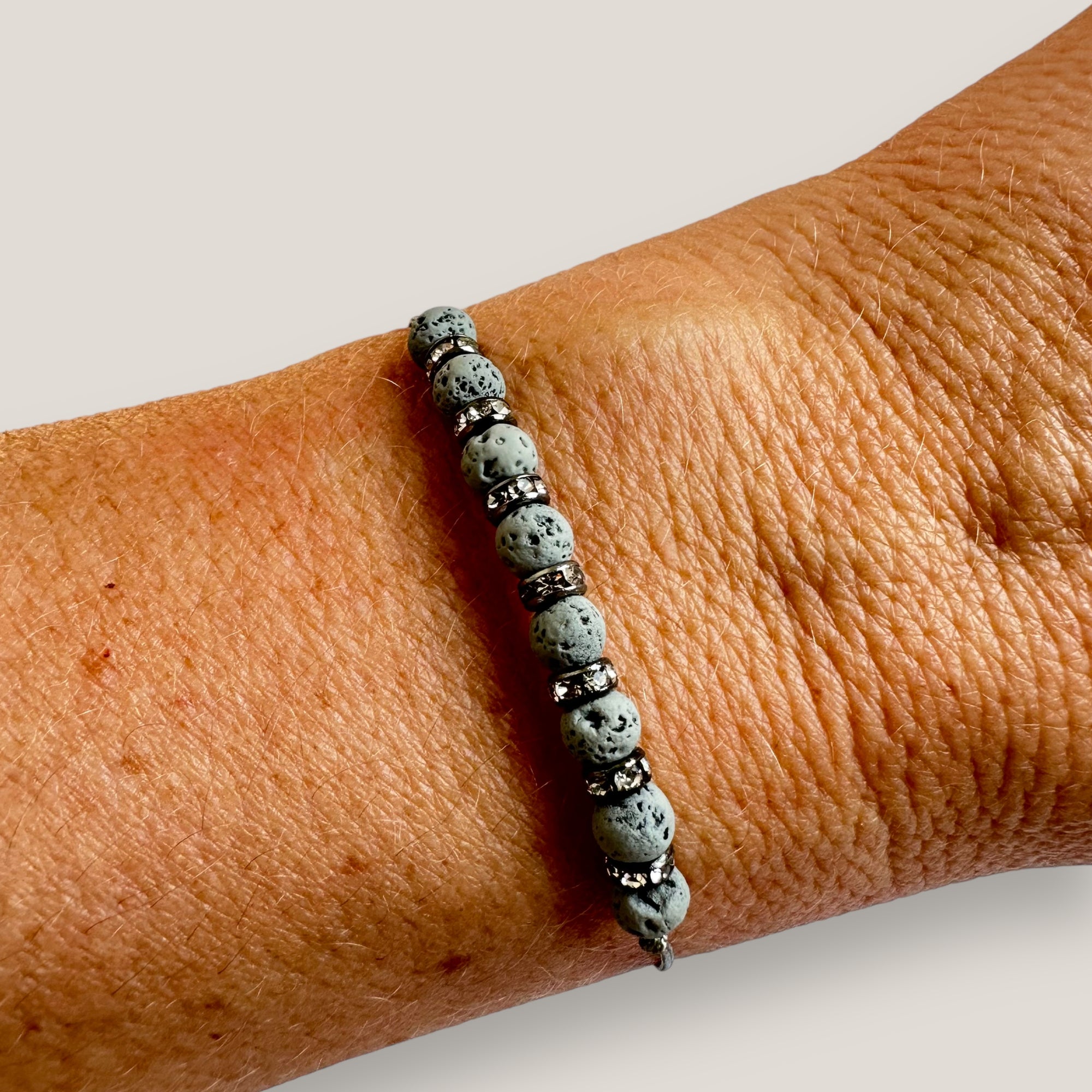 Pulsera minimal con ocho bolitas de lava gris claro y brillis blancos