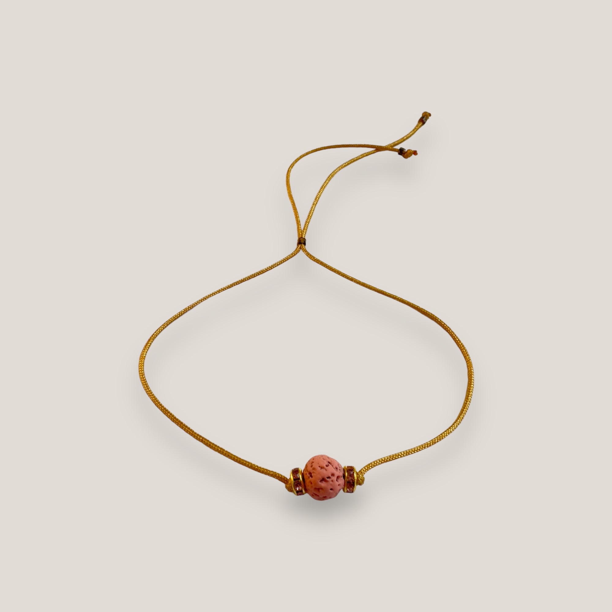 Pulsera minimal con bola de lava fucsia y cuentas doradas con brillis rosas