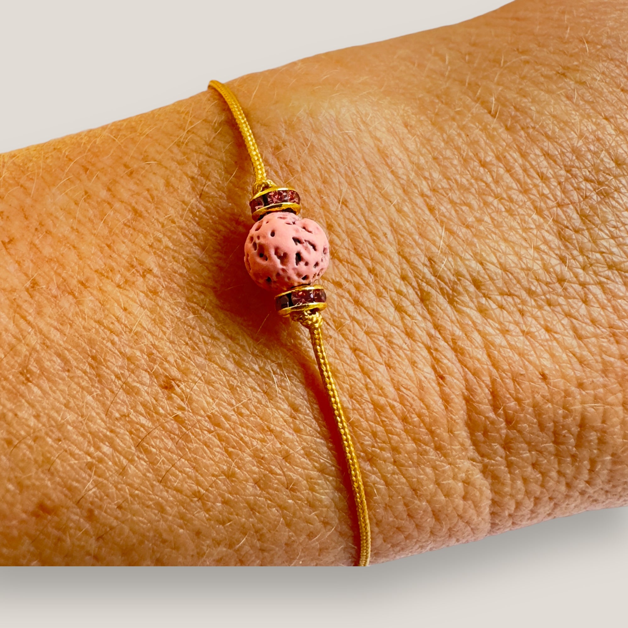 Pulsera minimal con bola de lava fucsia y cuentas doradas con brillis rosas