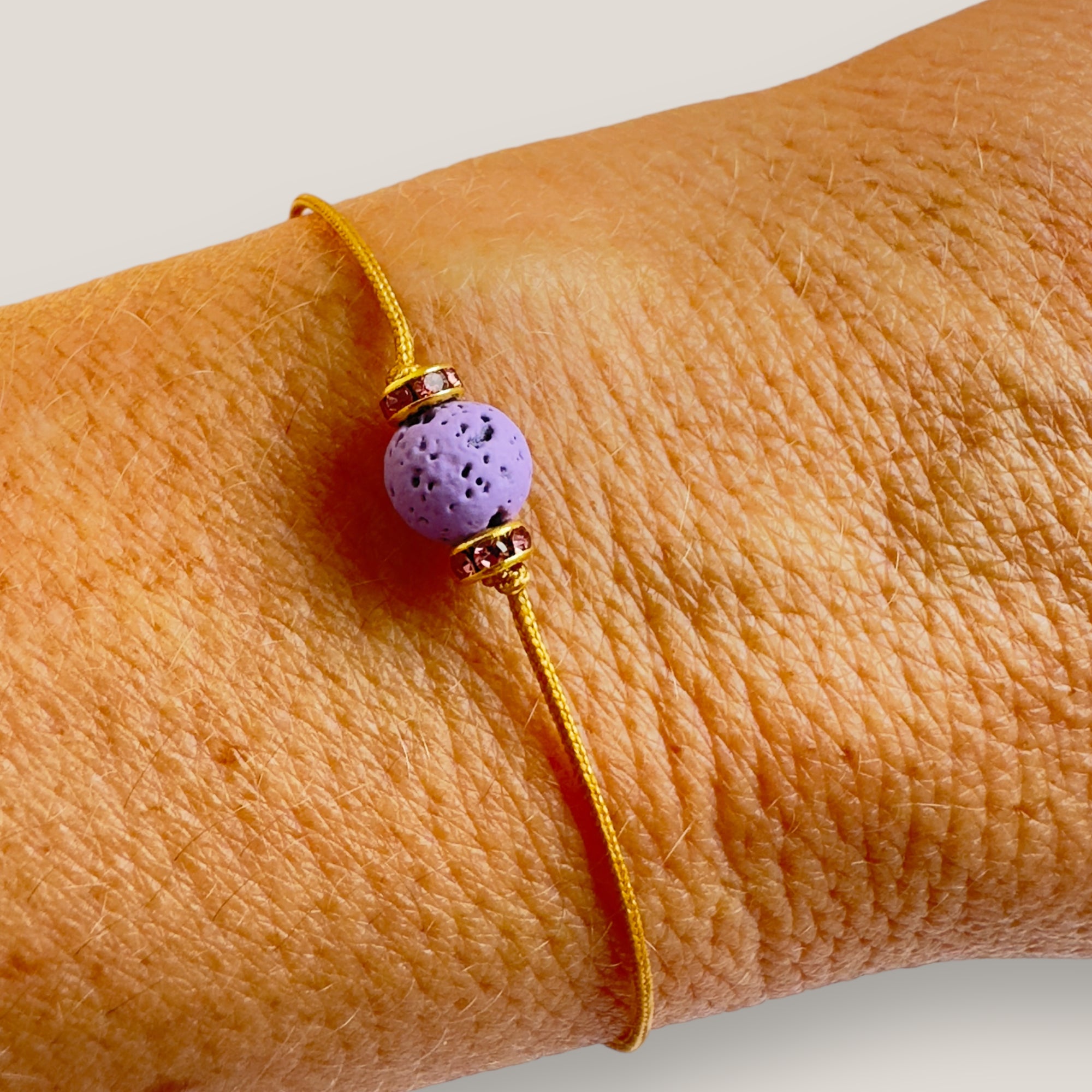 Pulsera minimal con bola de lava malva y cuentas doradas con brillis rosas