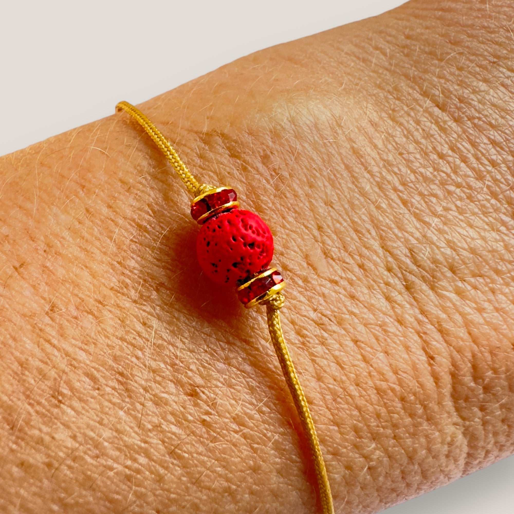 Pulsera minimal con bola de lava roja y cuentas doradas con brillis rojos