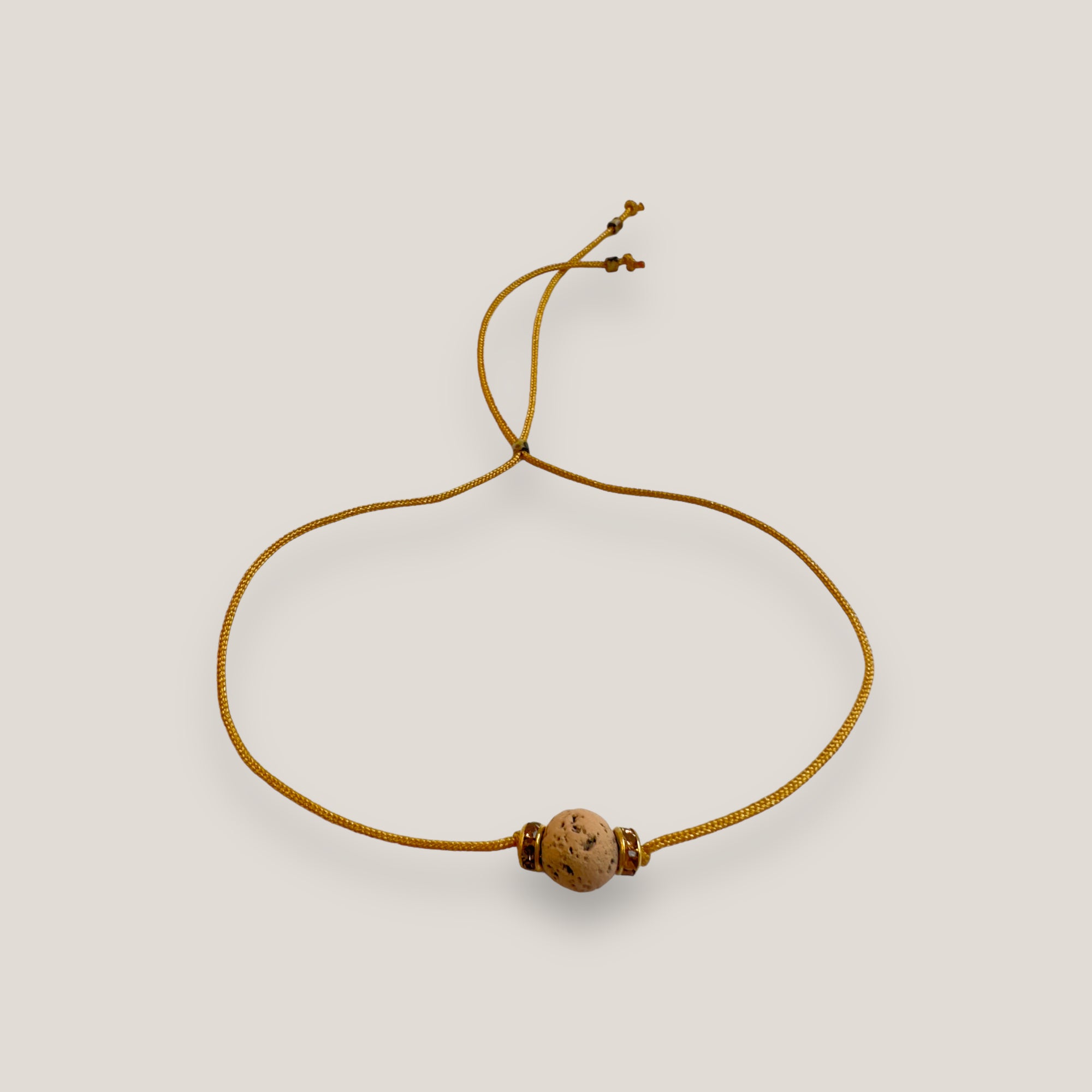 Pulsera minimal con bola de lava arena y cuentas doradas con brillis ámbar