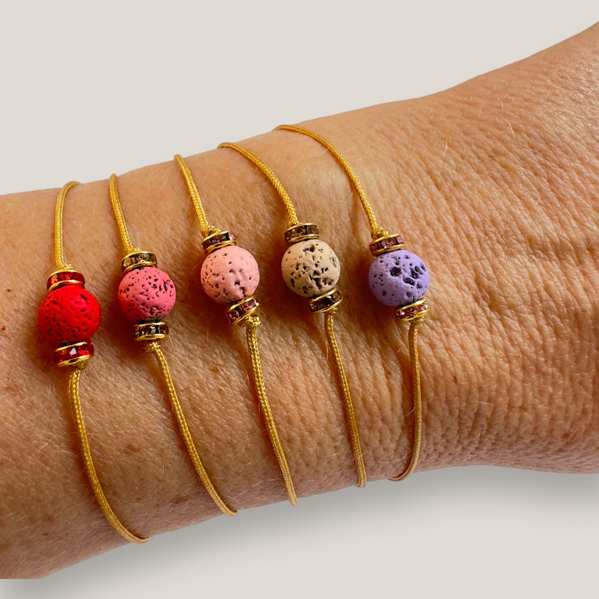 Pulsera minimal con bola de lava rosa y cuentas doradas con brillis rosas