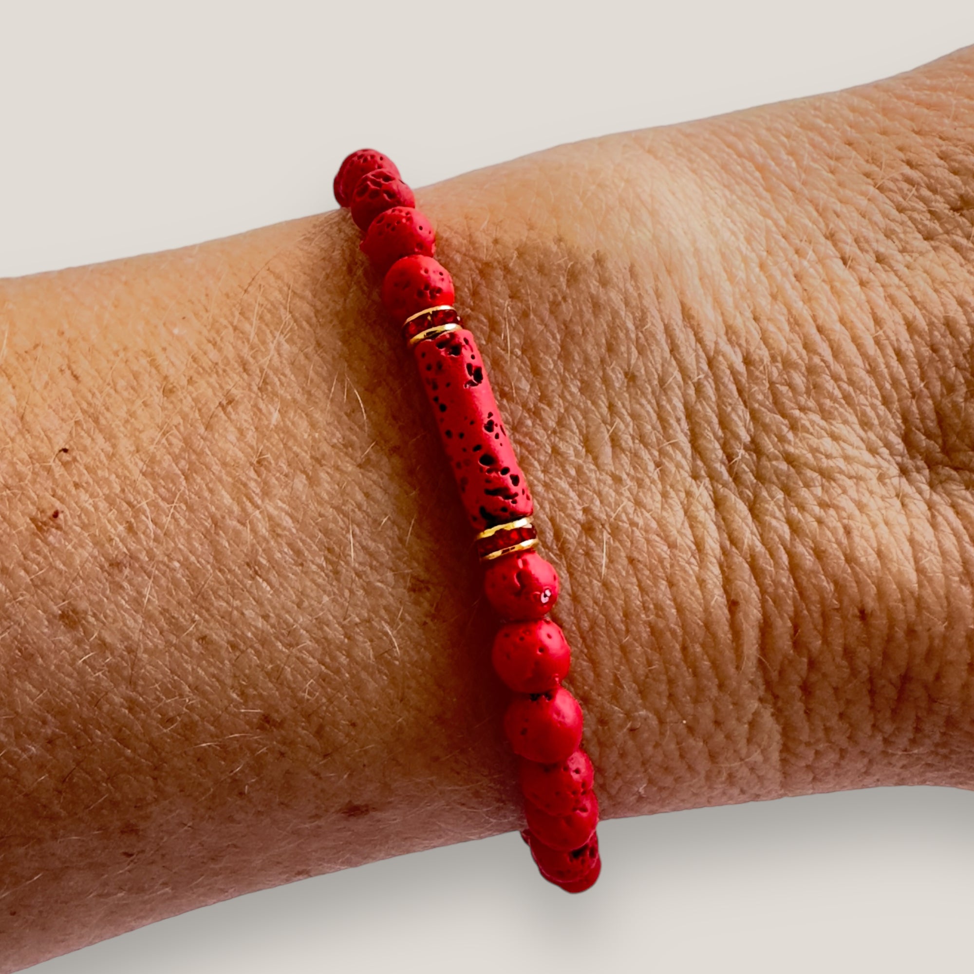 Pulsera con tubo, cuentas de lava roja y brillis oro con cristalitos rojos