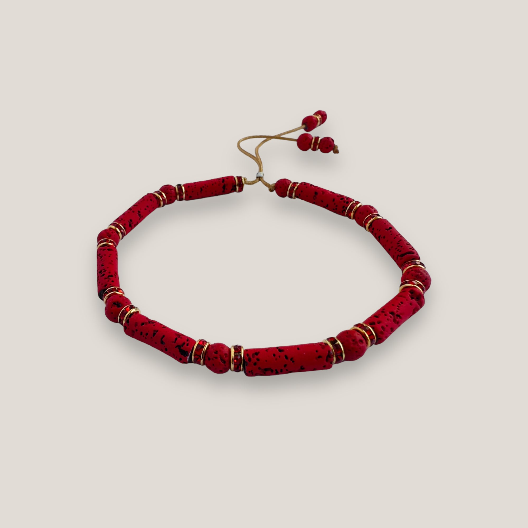 Pulsera con tubos y cuentas de lava roja y brillis oro con cristalitos rojos