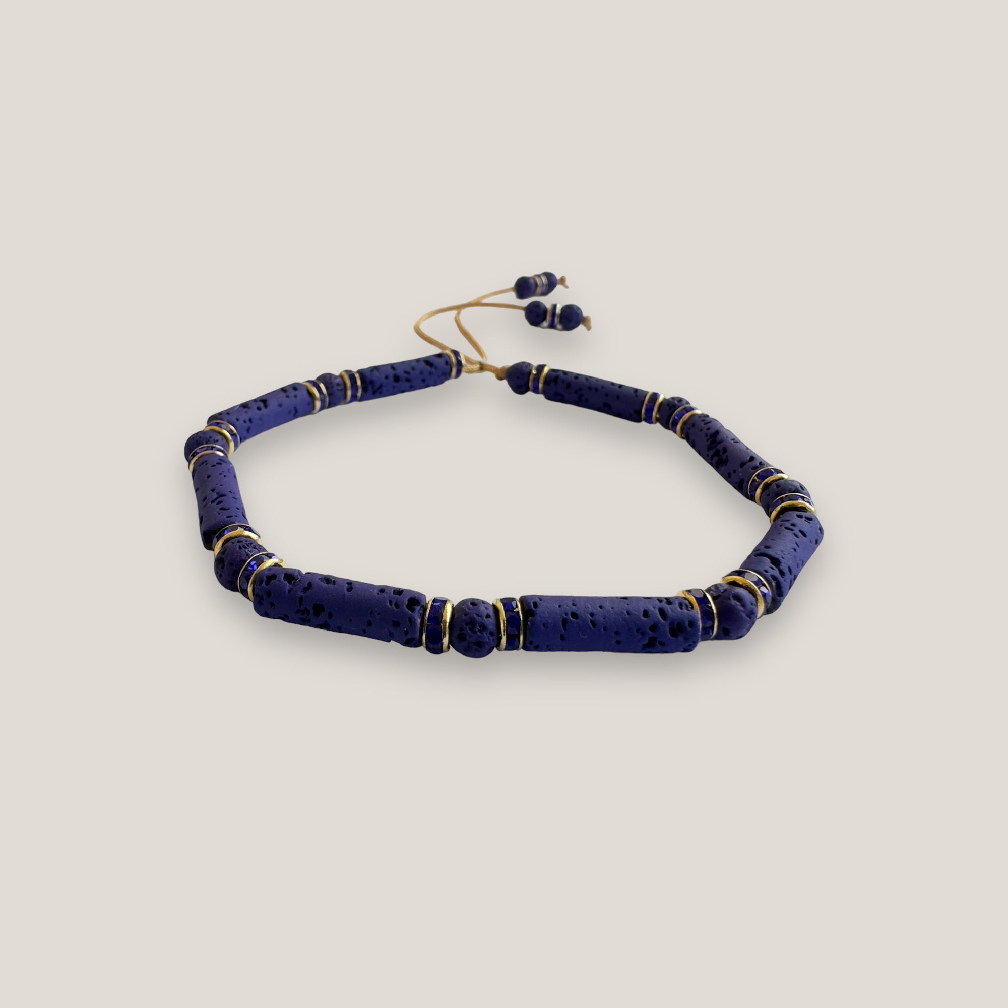 Pulsera con tubos y cuentas de lava azul profundoy brillis oro con cristalitos azules