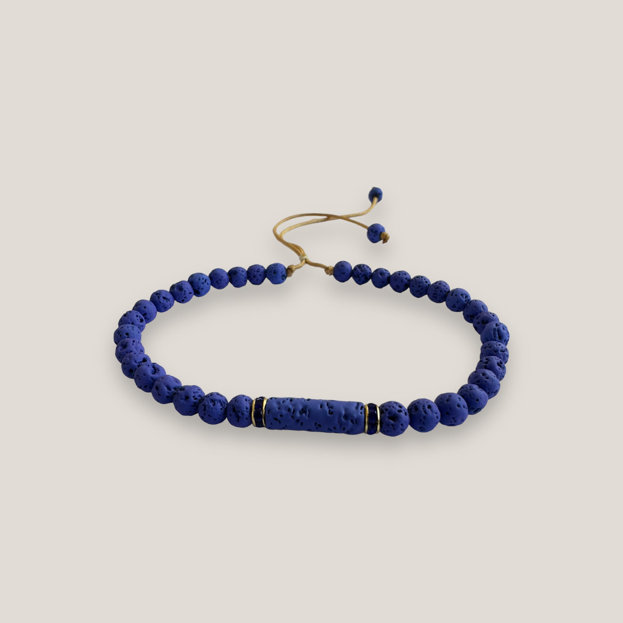 Pulsera con tubo, cuentas de lava en azulón y brillis oro con cristalitos azules