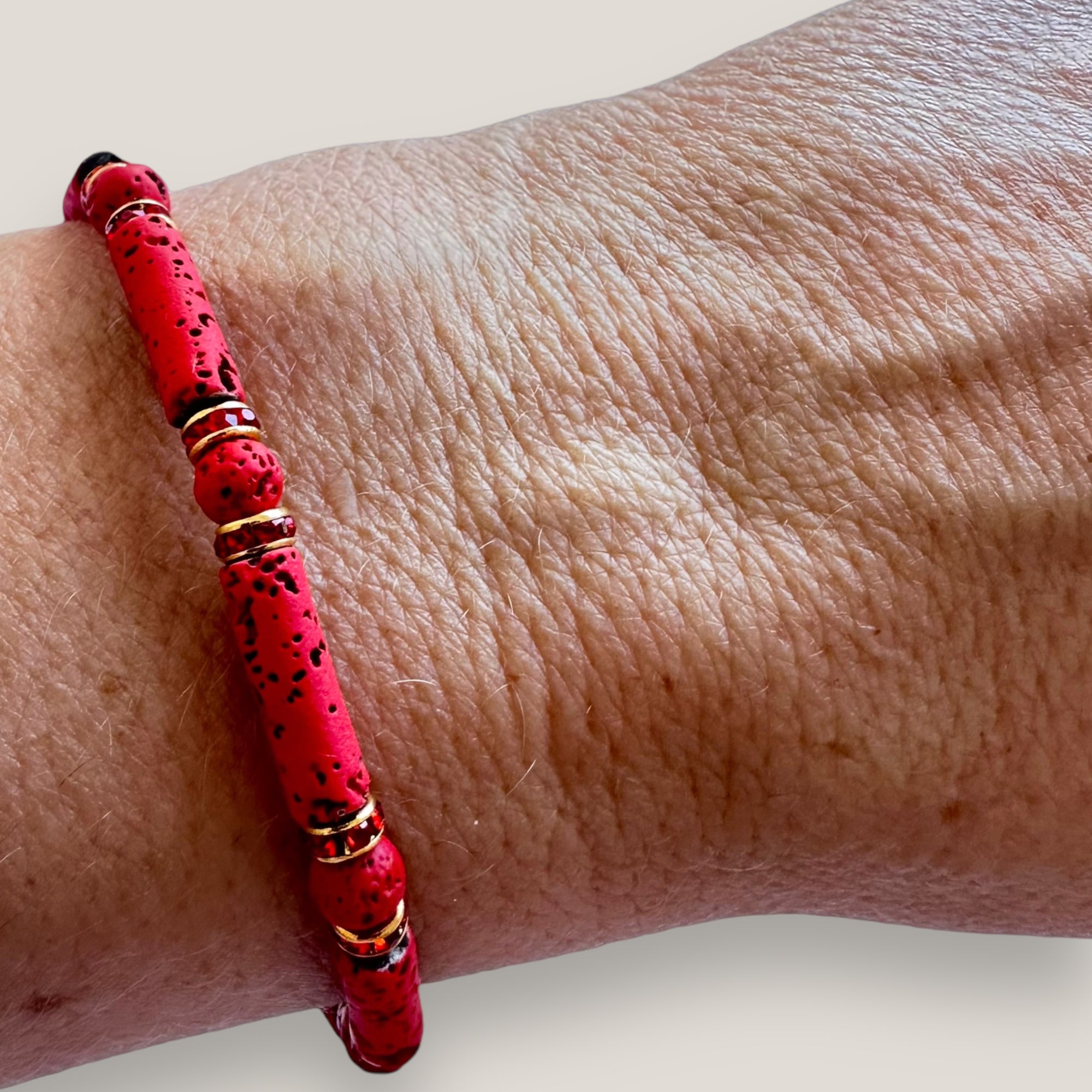 Pulsera con tubos y cuentas de lava roja y brillis oro con cristalitos rojos