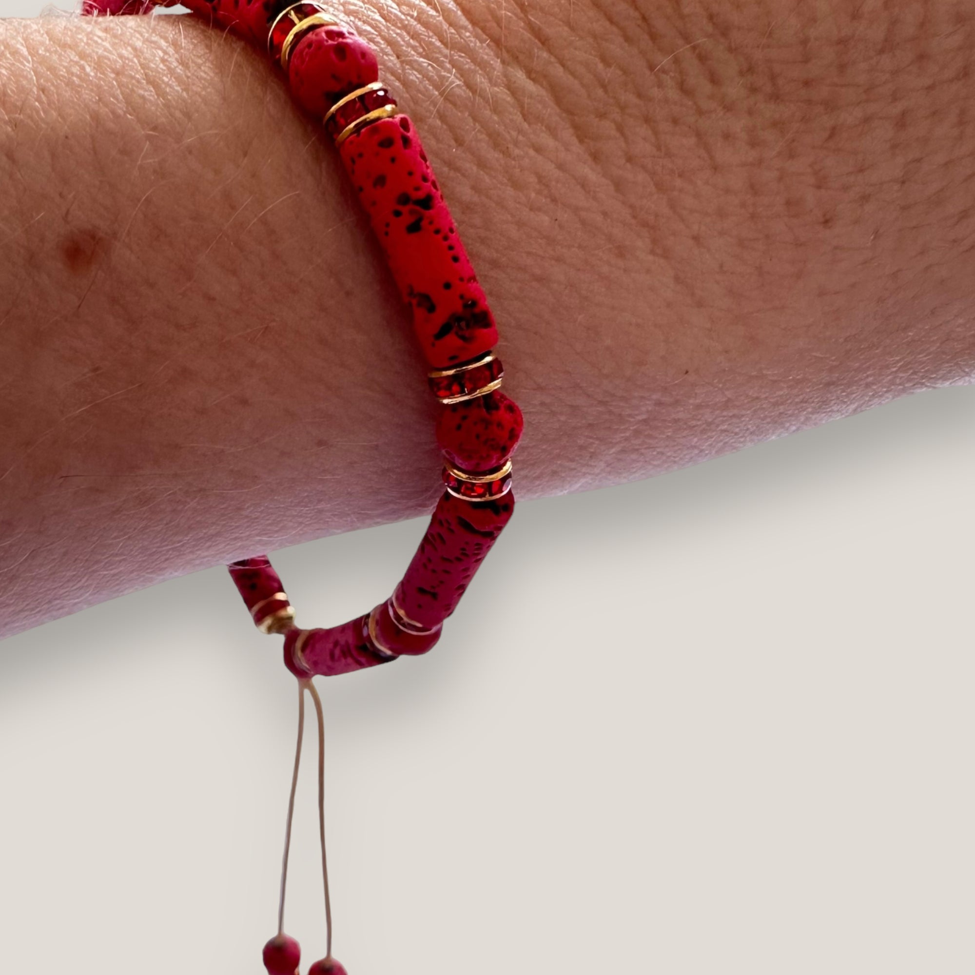 Pulsera con tubos y cuentas de lava roja y brillis oro con cristalitos rojos