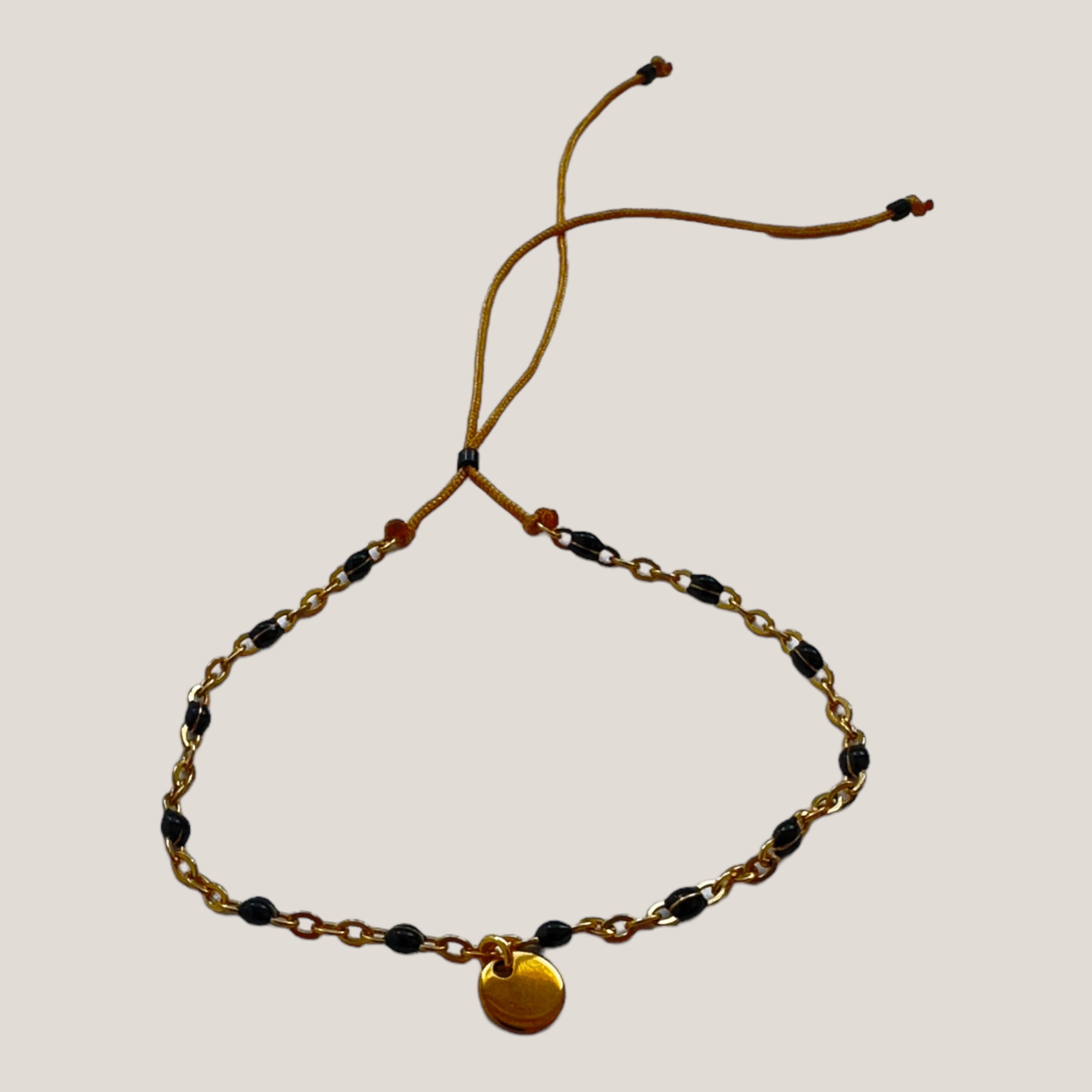 Kettenarmband und goldene Stahlmedaille mit schwarz emaillierten Kugeln