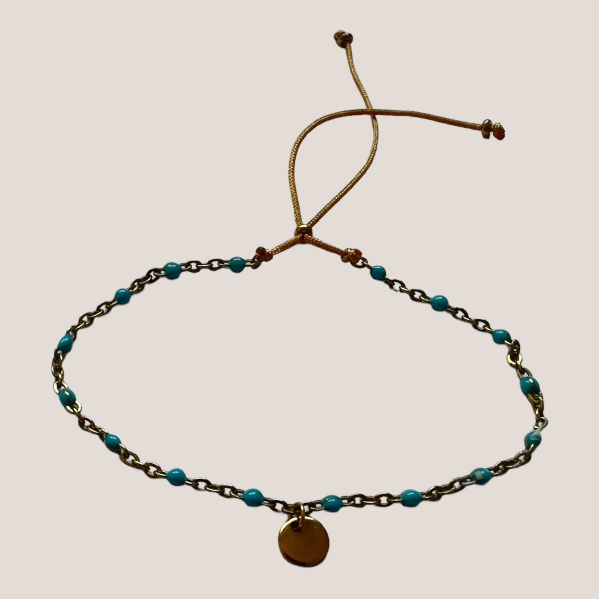 Kettenarmband und goldene Stahlmedaille mit türkisfarbenen emaillierten Kugeln