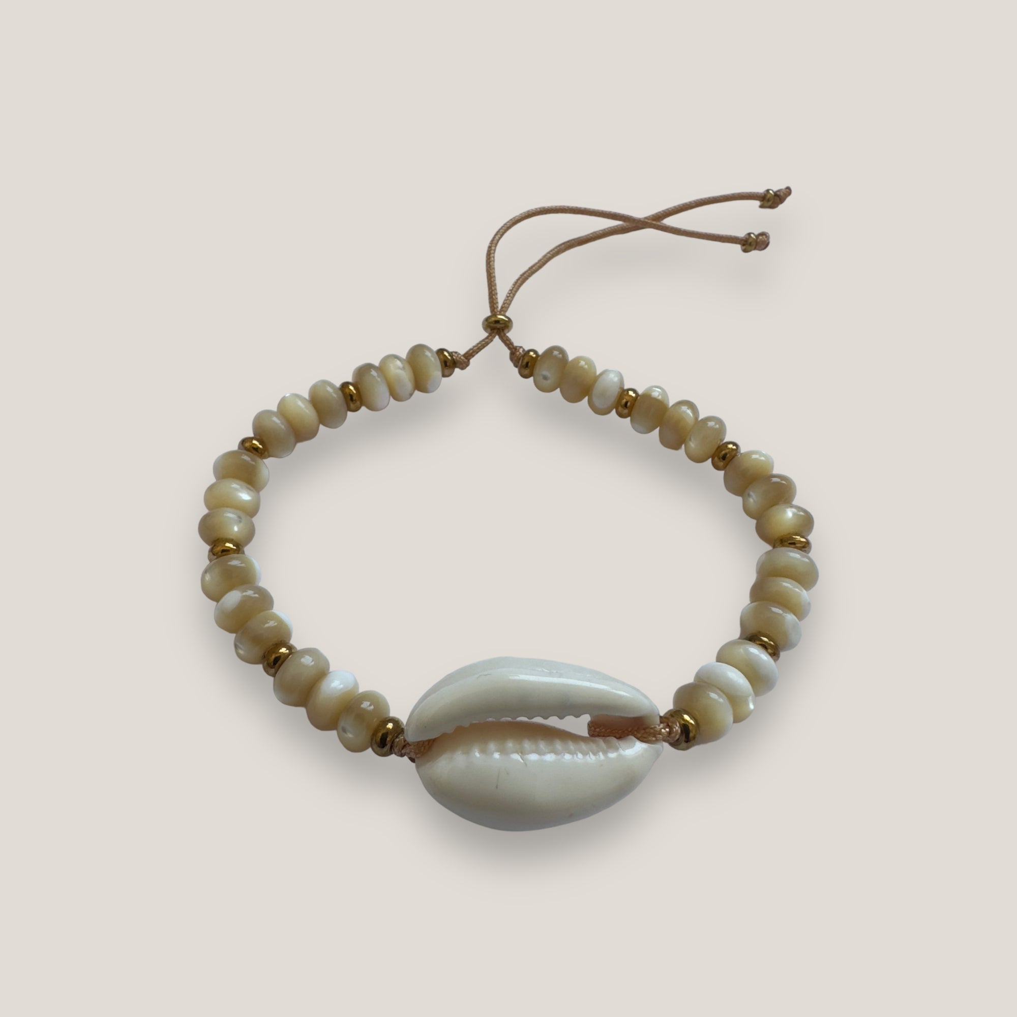 Armband mit weißer Kauri, 6 mm großen beigen Perlmuttscheiben und goldenen Stahlperlen