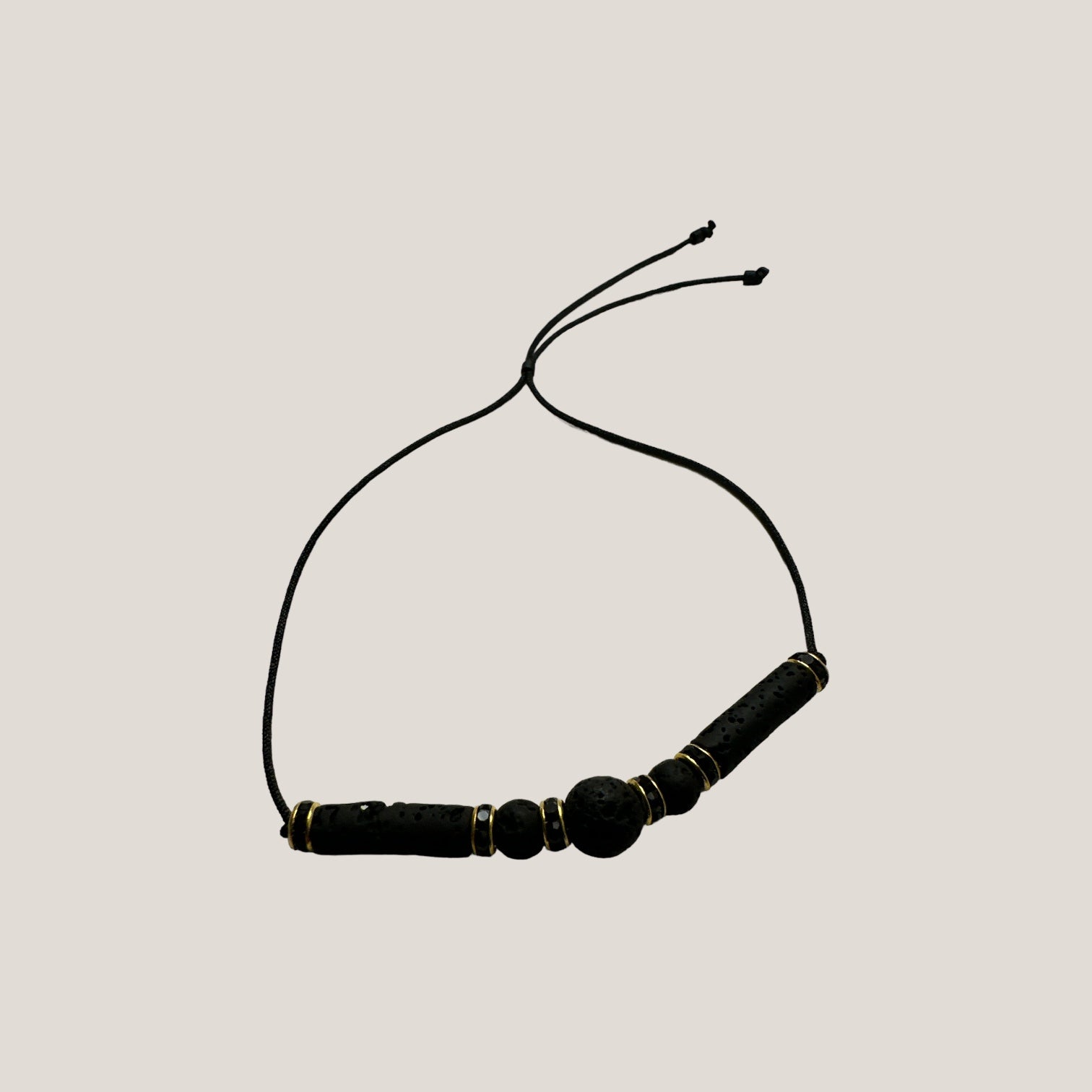 Pulsera minimal con una bola, dos bolitas y dos tubos de lava negra y brillis oro y cristal negro