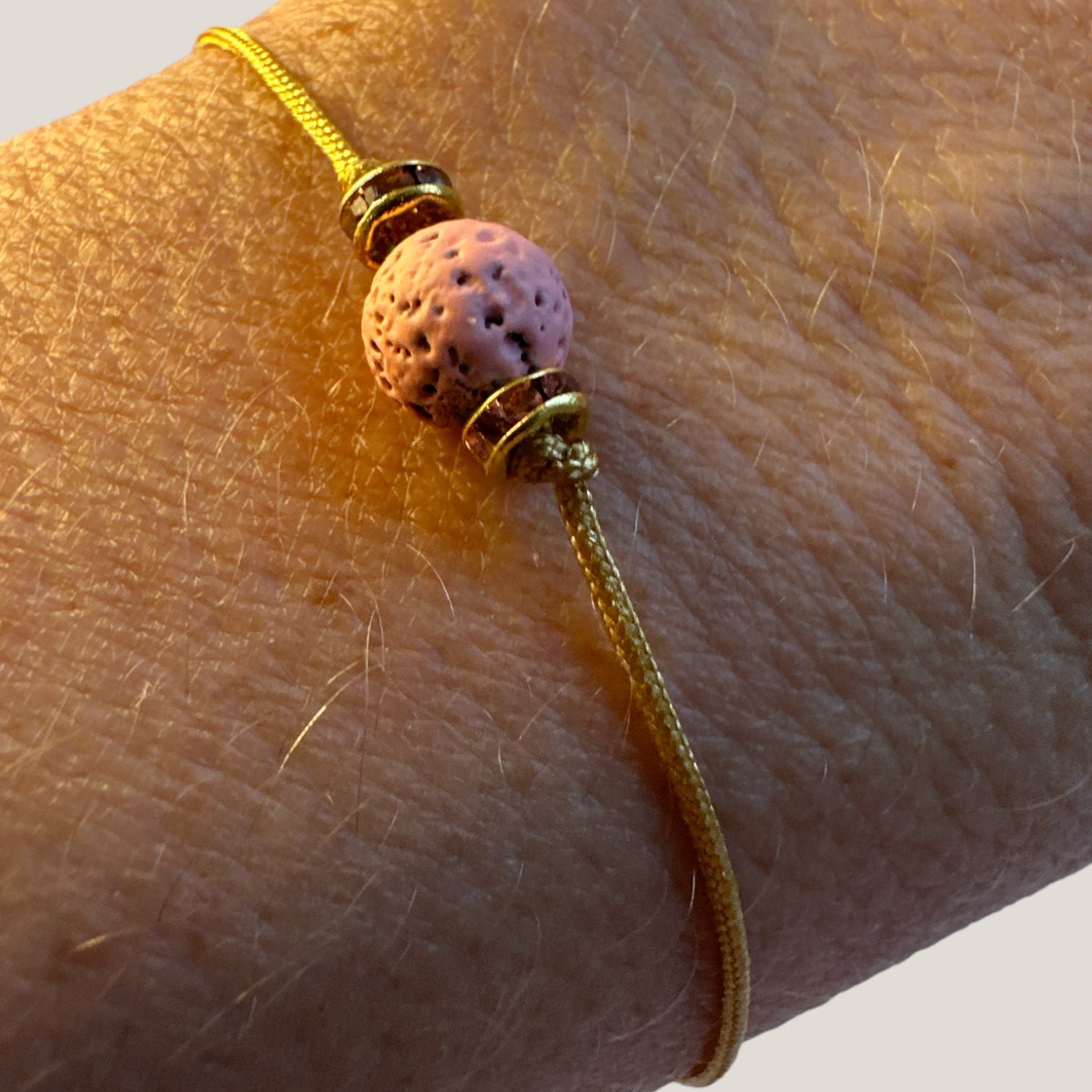 Pulsera minimal con bola de lava rosa y cuentas doradas con brillis rosas
