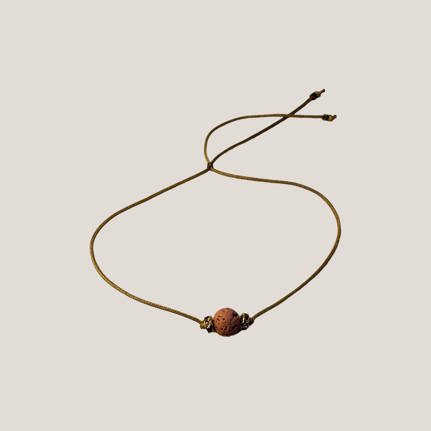 Pulsera minimal con bola de lava rosa y cuentas doradas con brillis rosas