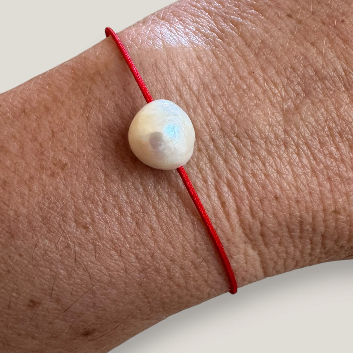 Pulsera minimal perla natural redondeada 10mm blanca cordón nailon rojo
