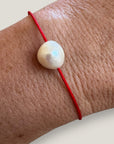 Pulsera minimal perla natural redondeada 10mm blanca cordón nailon rojo
