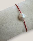 Pulsera minimal perla natural redondeada 10mm blanca cordón nailon rojo