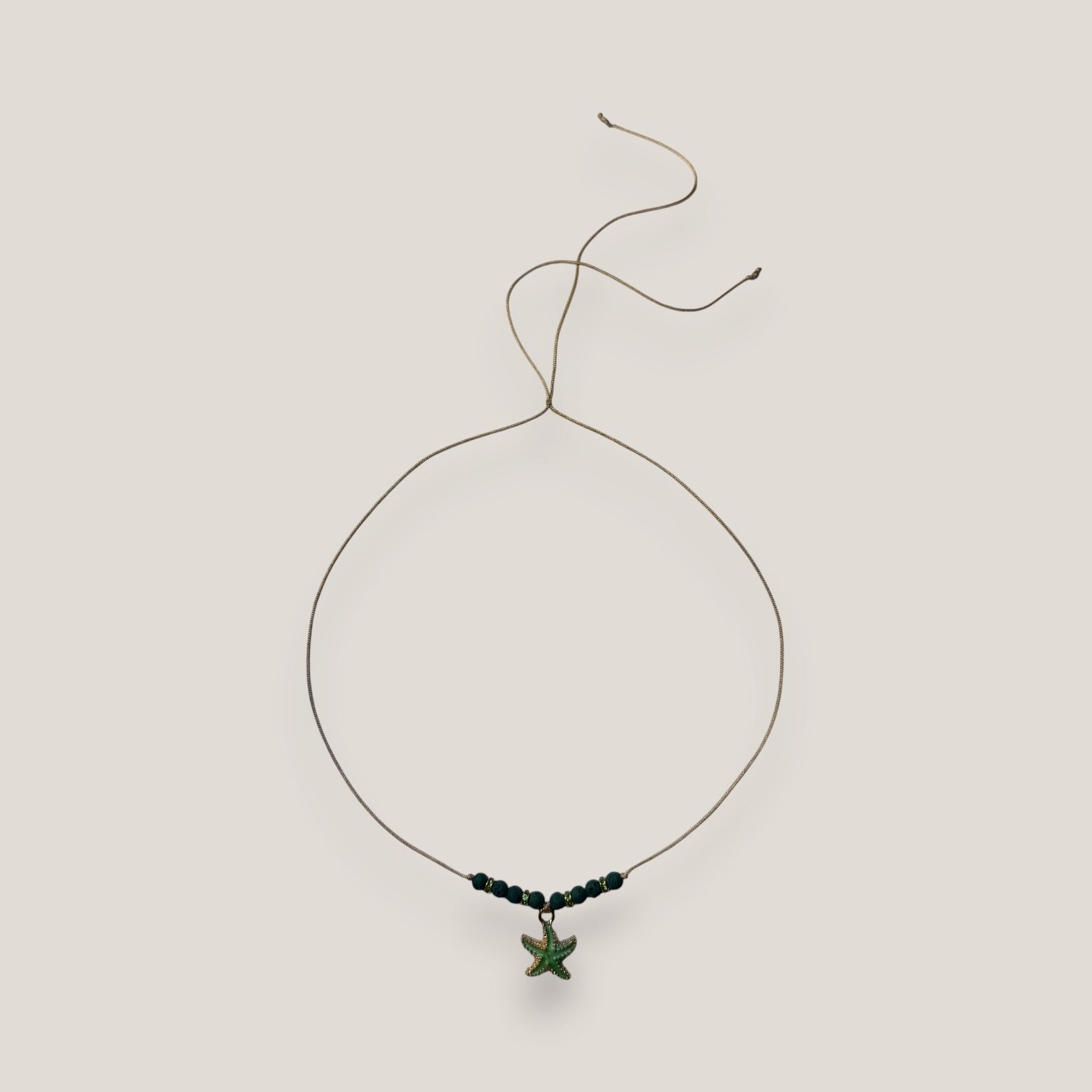 Collar midi con estrella dorada esmaltada en verde con lava verde oscuro y separadores dorados con cristalitos verde olivina