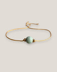 Minimalistisches Armband mit einer 8 mm großen türkisfarbenen Schwammkorallenkugel und goldenen Trennelementen mit funkelnden weißen Kristallen.