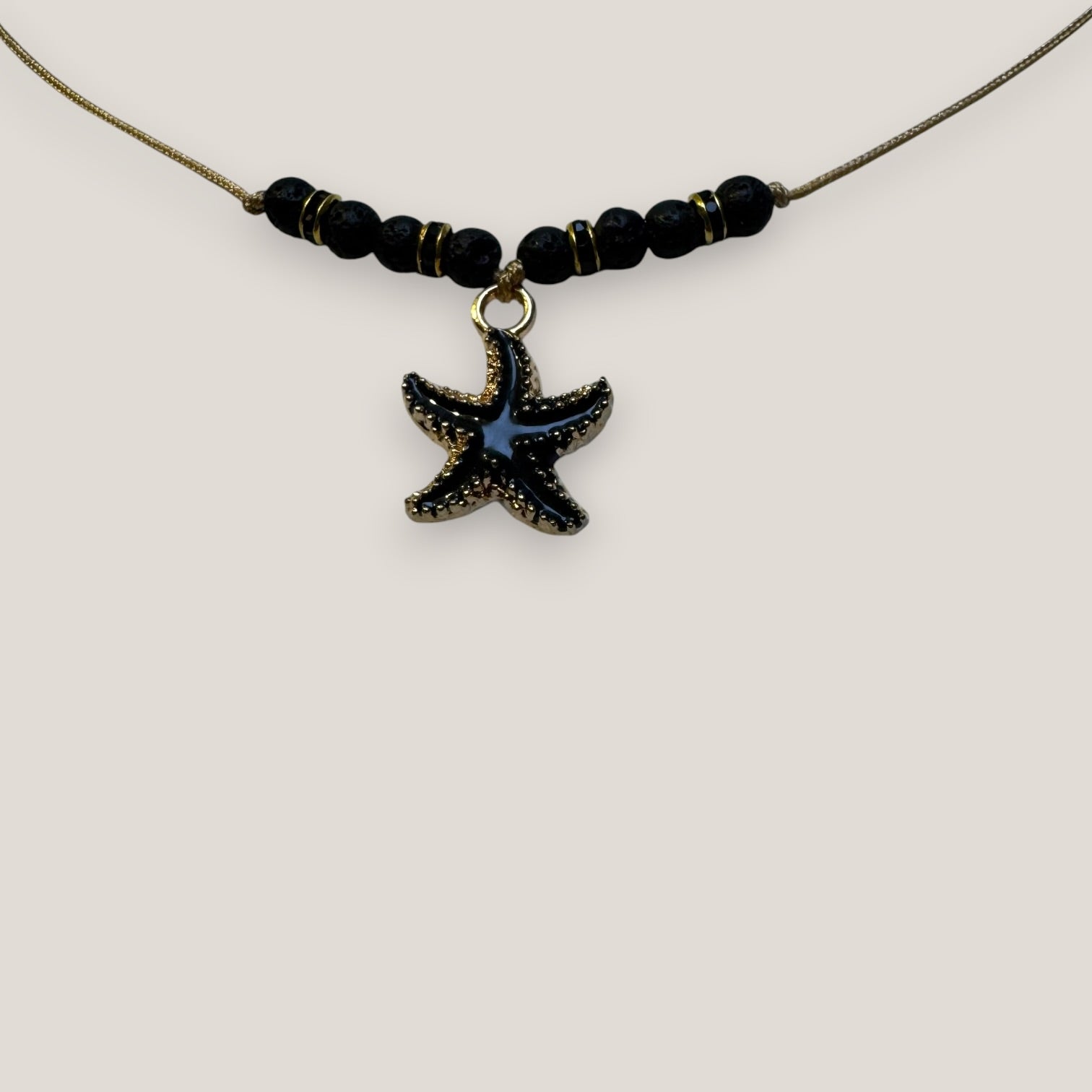 Collar midi con estrella dorada esmaltada en negro lava negra y separadores dorados con cristalitos negros
